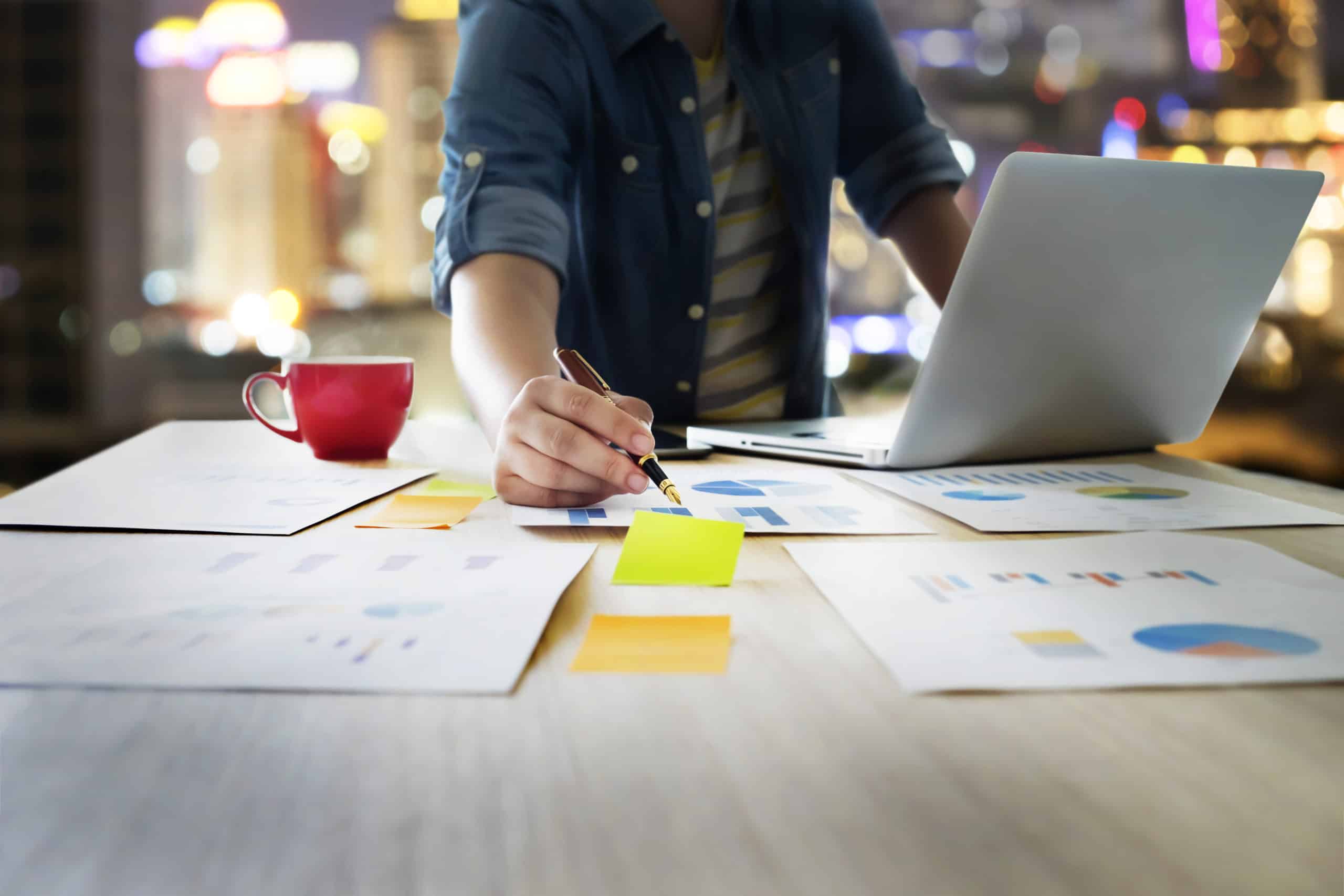 Startup business people using laptop and summery business chart to analyze marketing situation. Working people doing overtime at night in office.